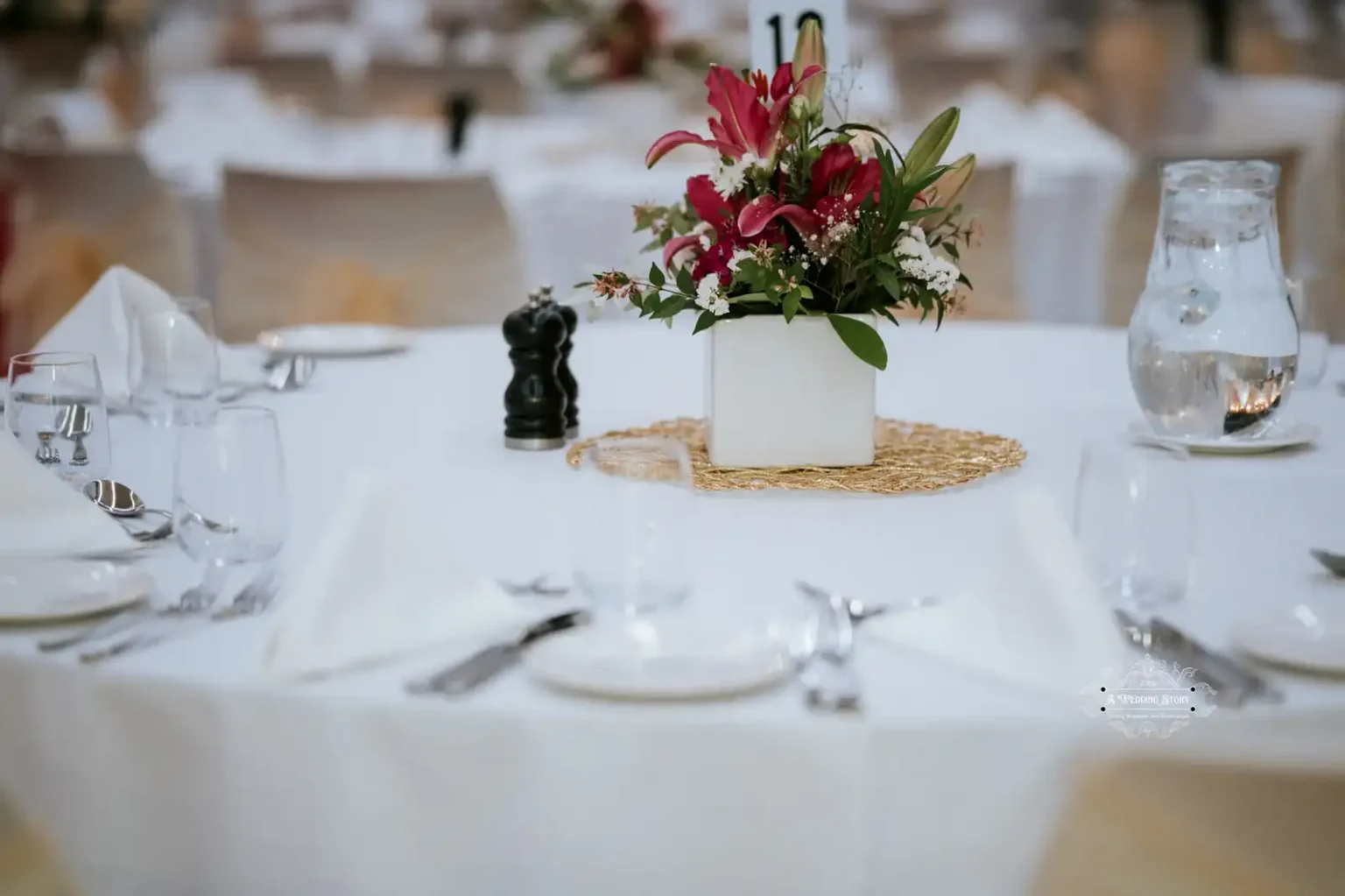 Elegant wedding table setup with a floral centerpiece in a white vase, surrounded by glassware and cutlery, captured in Wellington.