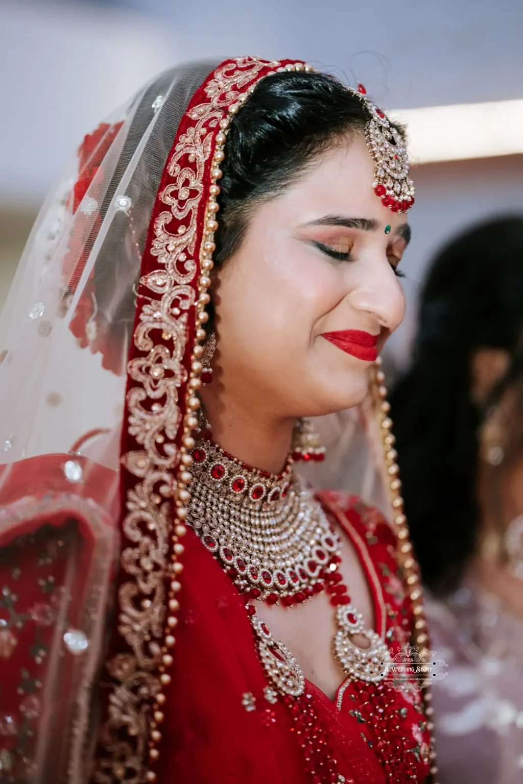 Close-up of a smiling bride in traditional red attire, with closed eyes, capturing a moment of emotion on her wedding day.