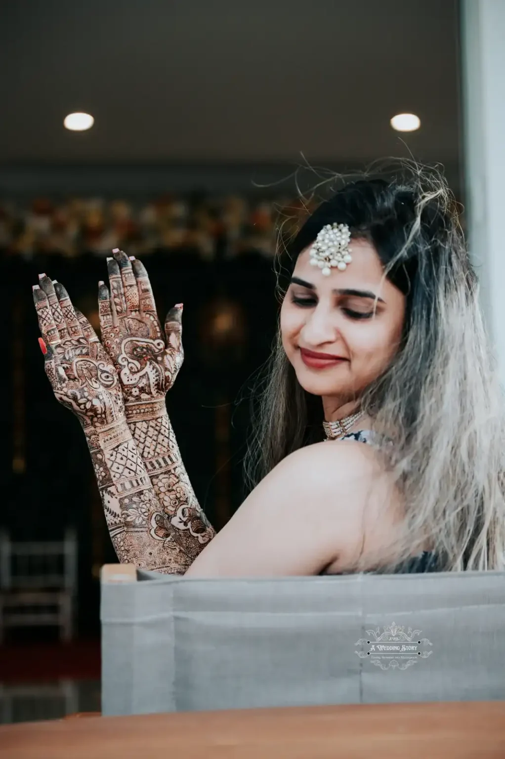 Smiling bride elegantly displaying intricate mehndi designs on her hands during a pre-wedding celebration in Wellington, captured by A Wedding Story