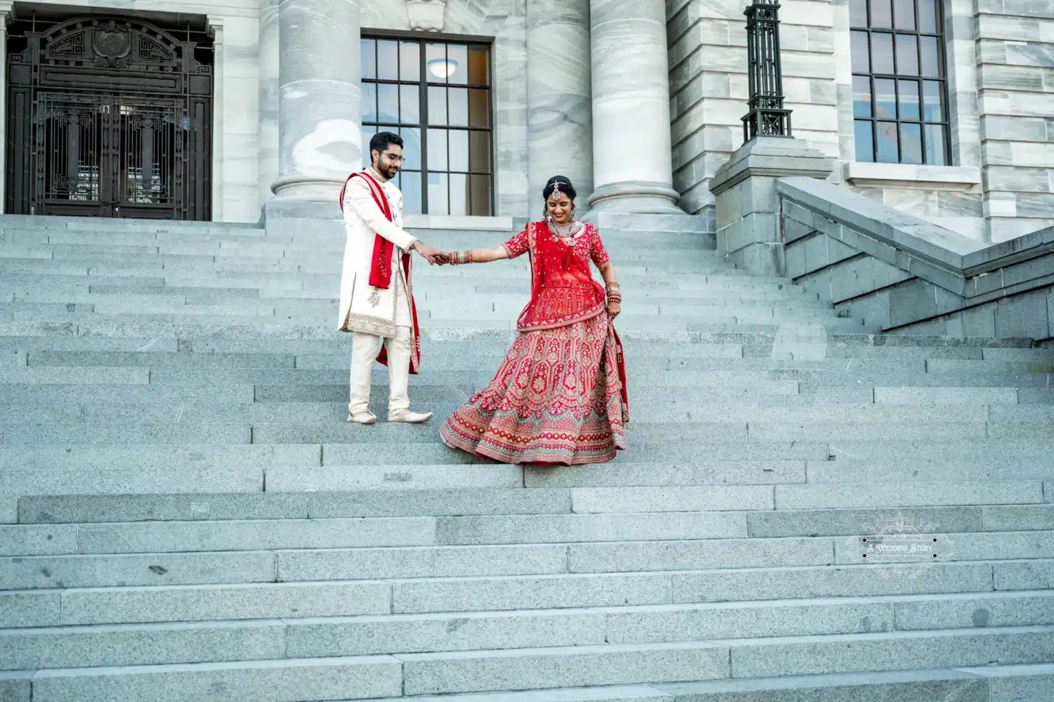 Groom helping bride down the steps of a historic building in Wellington, New Zealand.