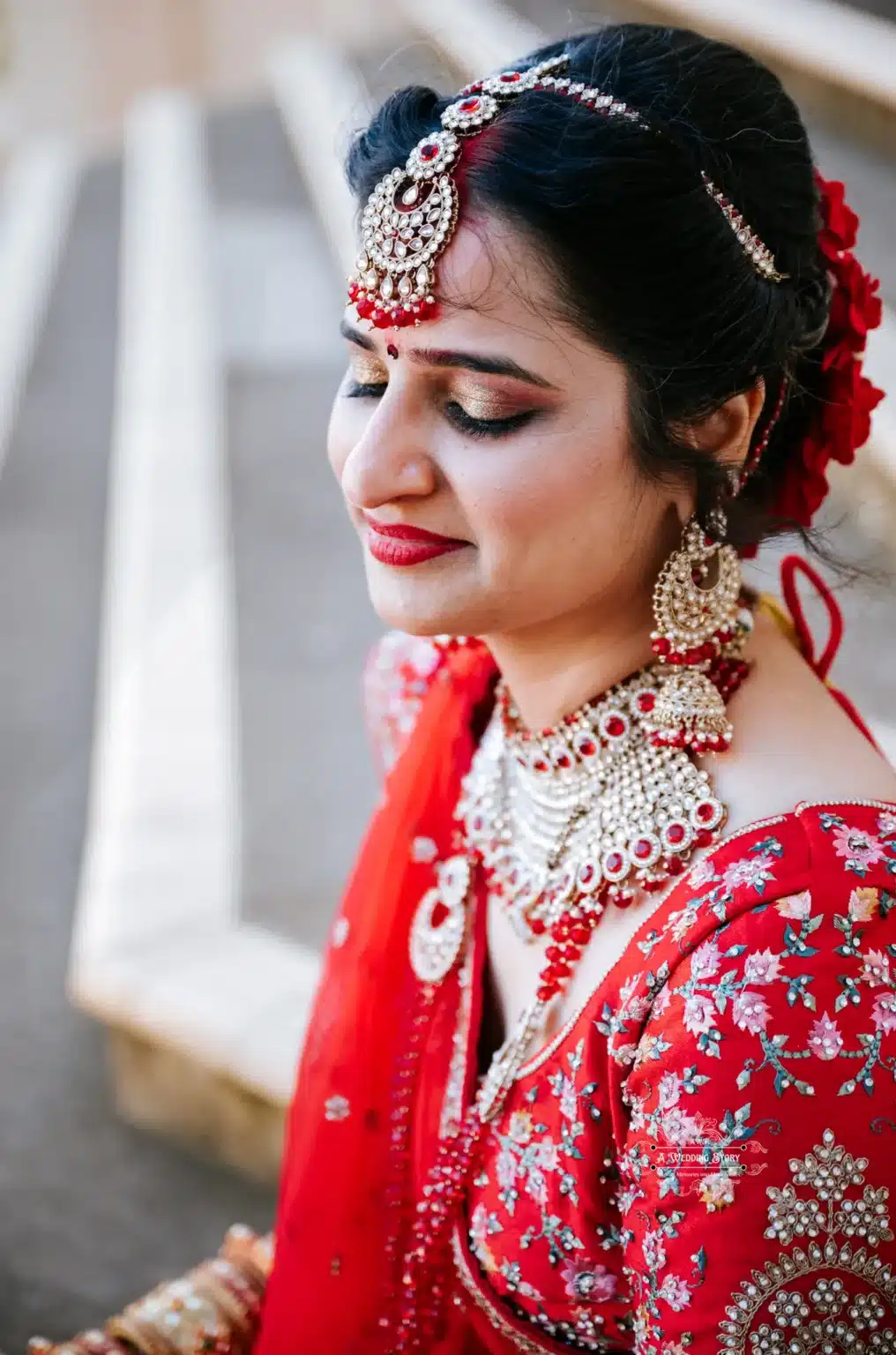 Indian bride in traditional red attire with intricate jewelry and a serene expression, captured in Wellington by Wedding Photography.