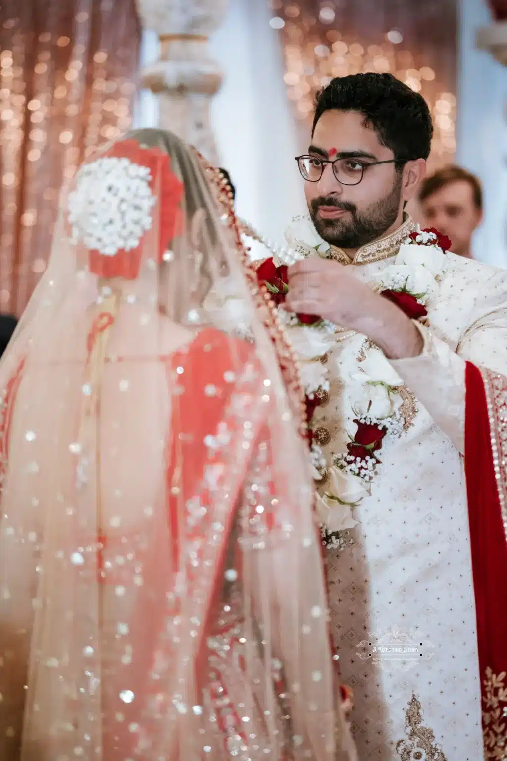 Groom in traditional attire drapes a garland on the bride as part of the wedding ritual, symbolizing unity and love.