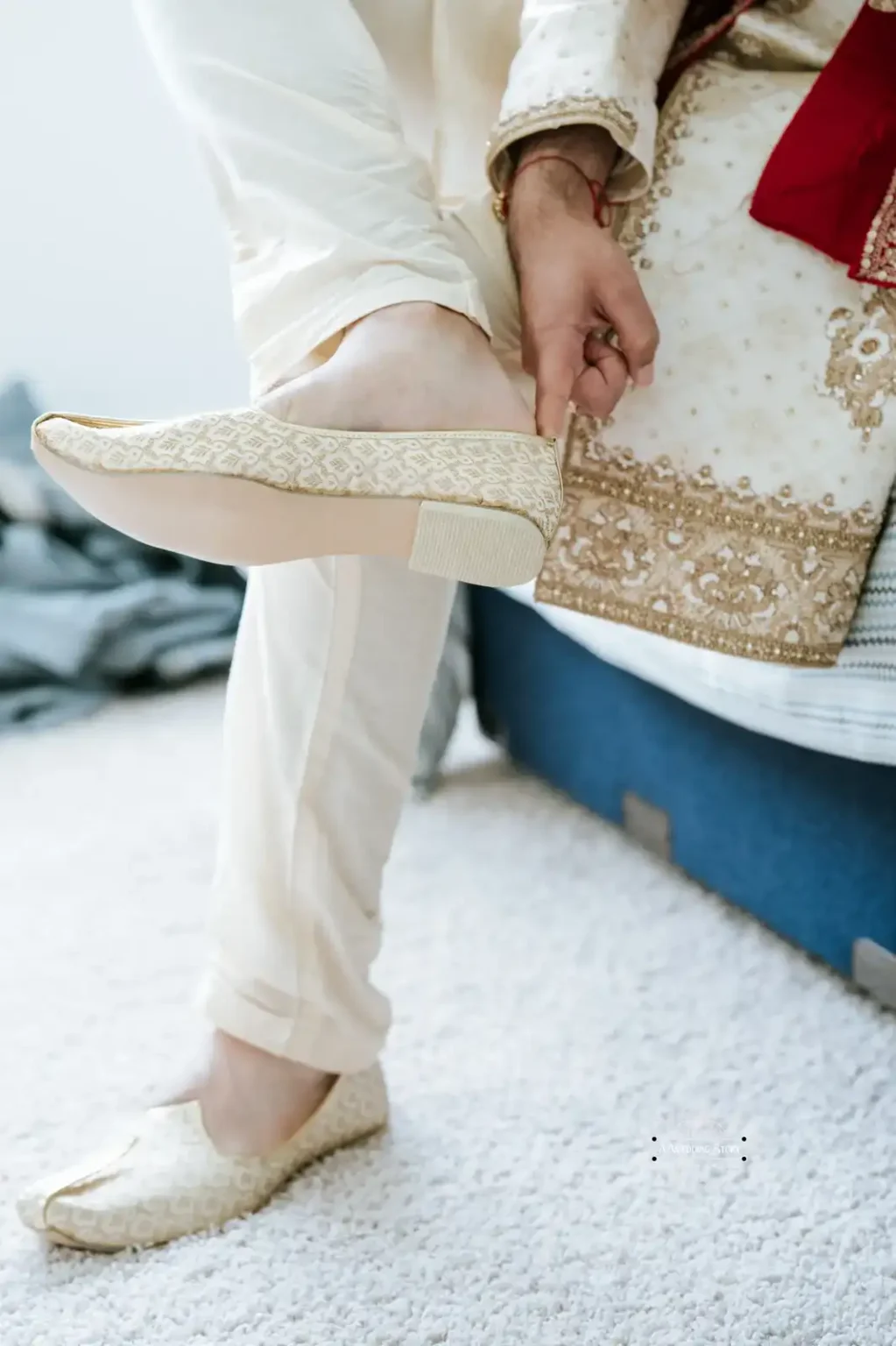 Indian groom putting on traditional embroidered wedding shoes, captured in Wellington by Wedding Photography.