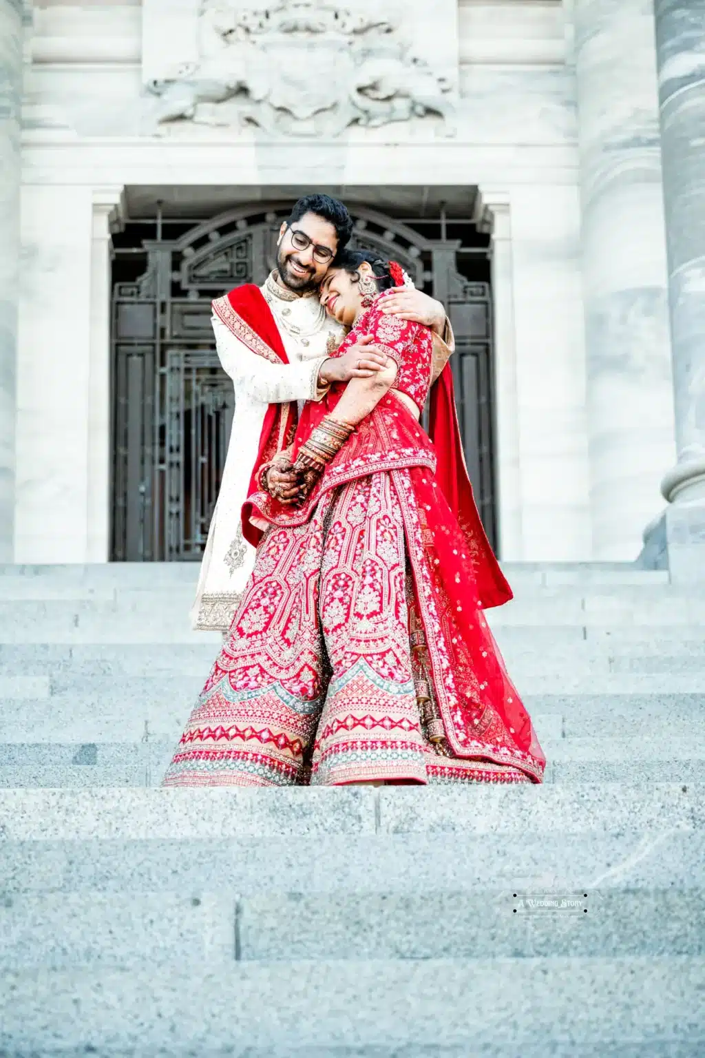 Bride and groom in a warm embrace on the steps of a historic building in Wellington, New Zealand.