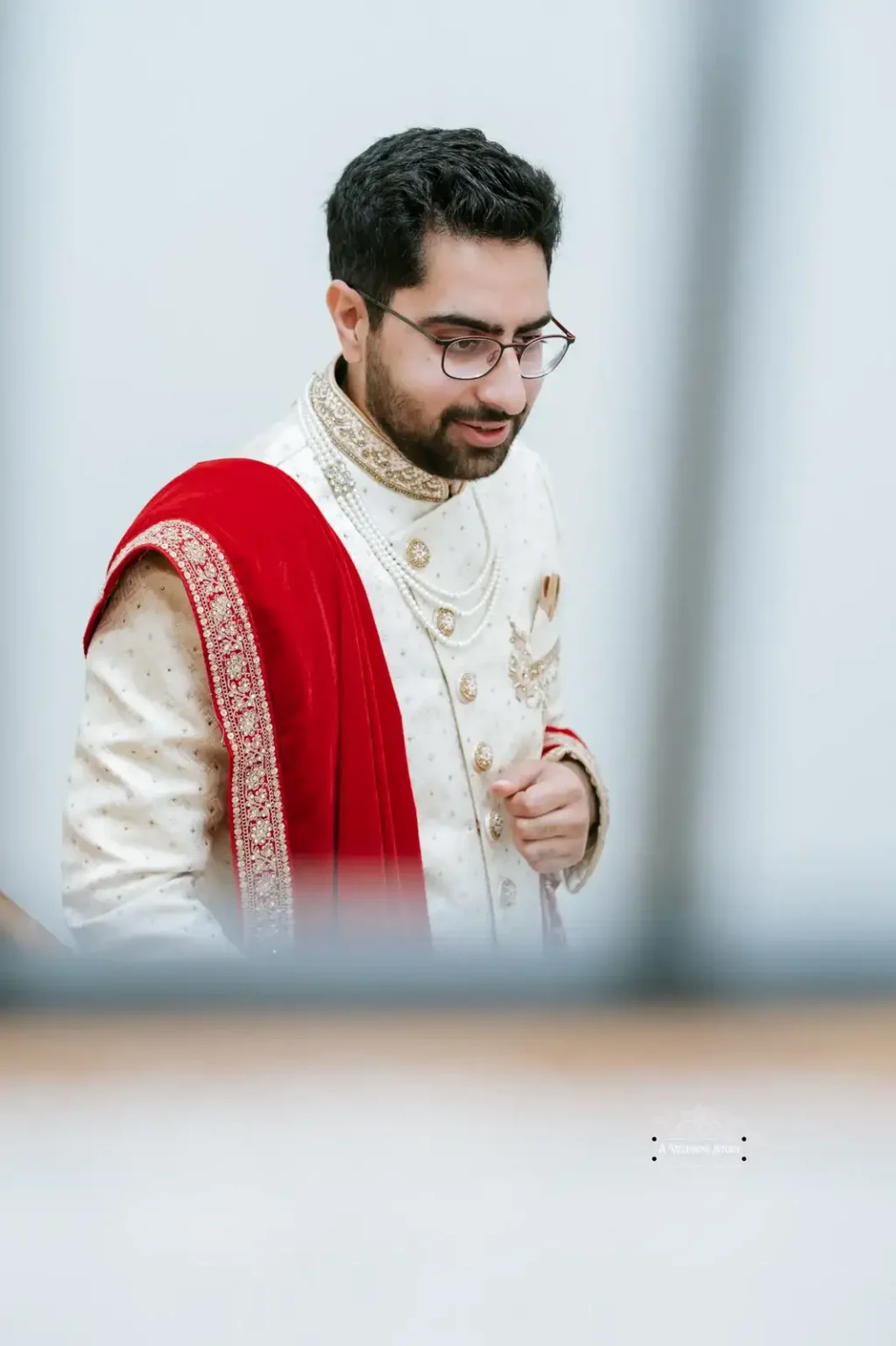 Indian groom in traditional wedding attire, featuring a red shawl, captured in Wellington by Wedding Photography.