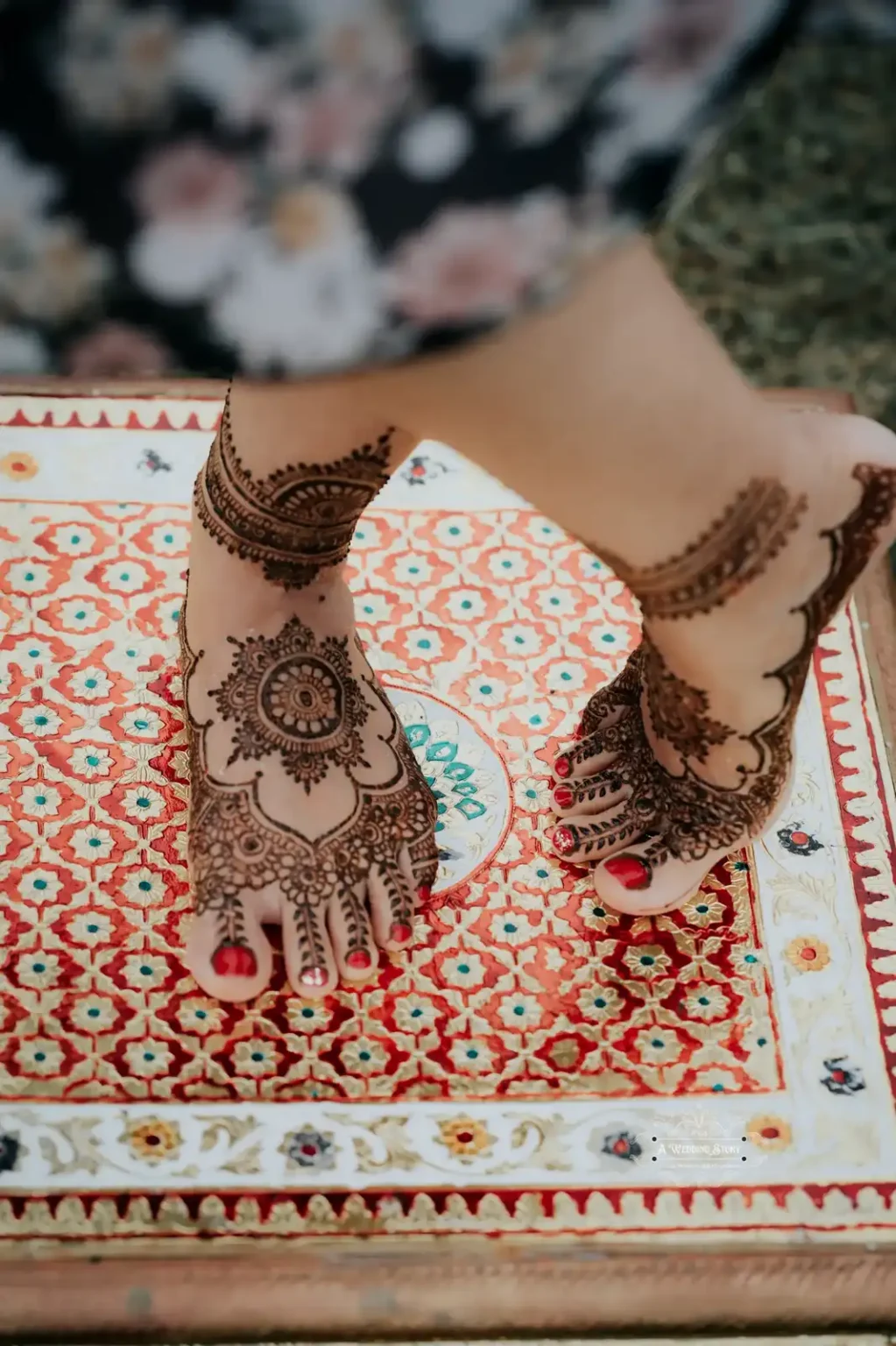 Close-up of a bride's feet adorned with intricate mehndi designs, placed on a colorful traditional mat, captured during a pre-wedding celebration in Wellington by A Wedding Story