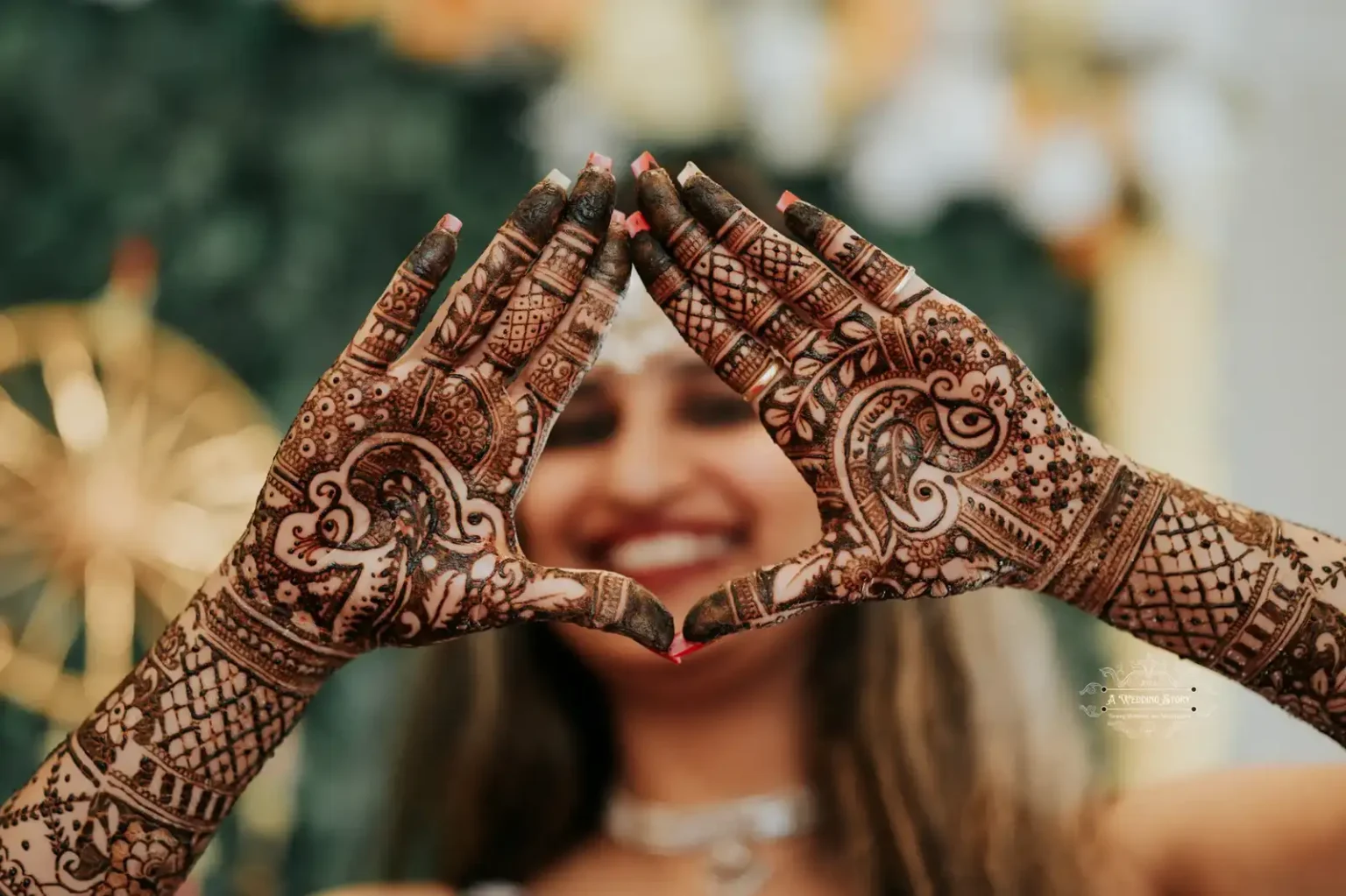 Close-up of a bride’s intricate mehndi designs forming a heart shape with her hands during a pre-wedding celebration, captured by A Wedding Story in Wellington