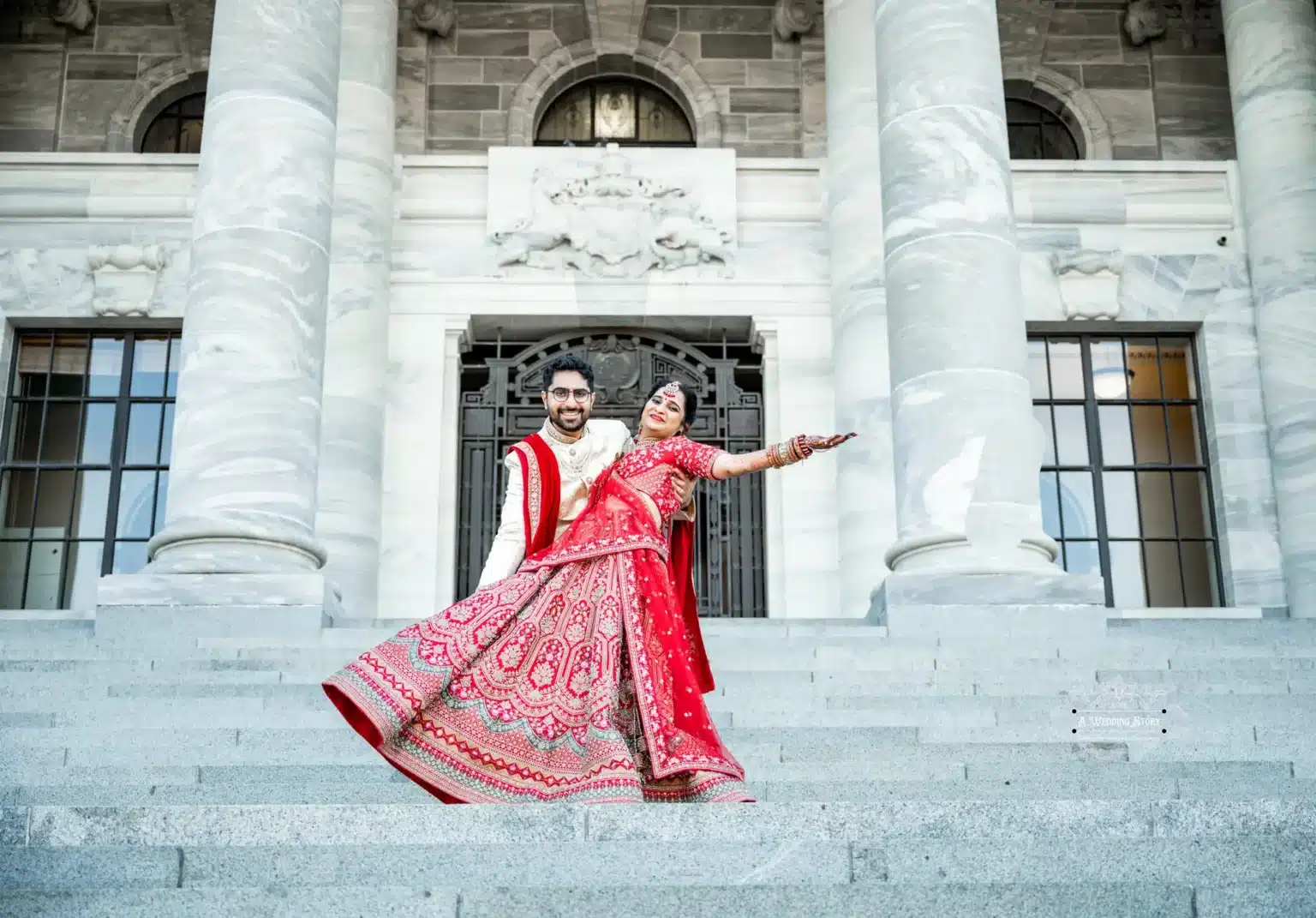 Bride and groom celebrating their wedding day with a playful dance on the steps of a historic building in Wellington, New Zealand.