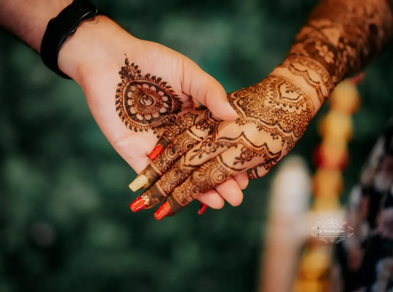 Close-up of a bride and groom holding hands, showcasing intricate bridal mehndi designs, captured during a pre-wedding ceremony in Wellington by A Wedding Story