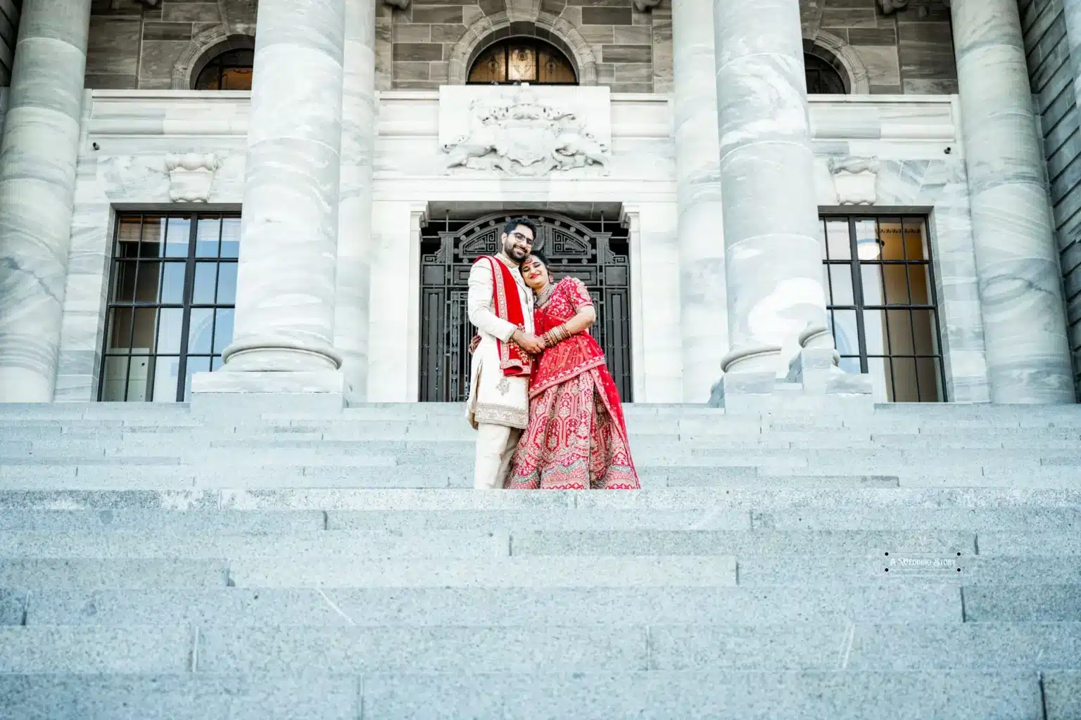 Wedding couple embracing on the steps of a grand building in Wellington, New Zealand.