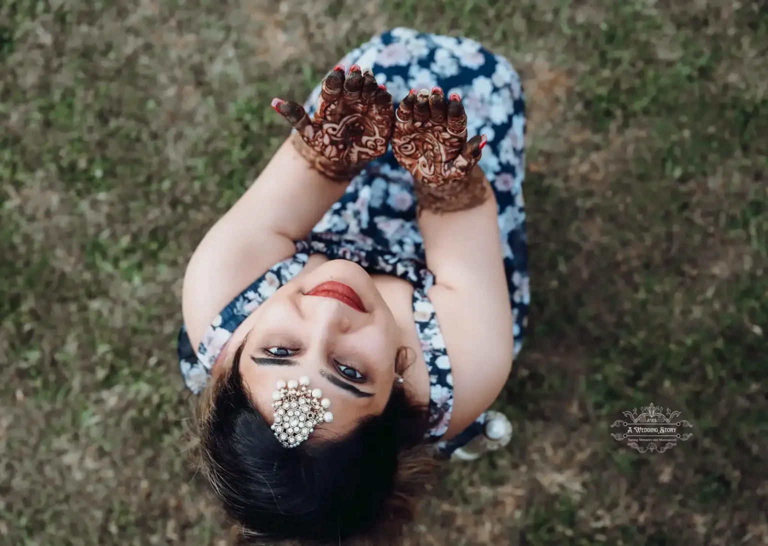 Overhead shot of a bride smiling while showing her intricate mehndi designs on her hands during a pre-wedding celebration, captured by A Wedding Story in Wellington