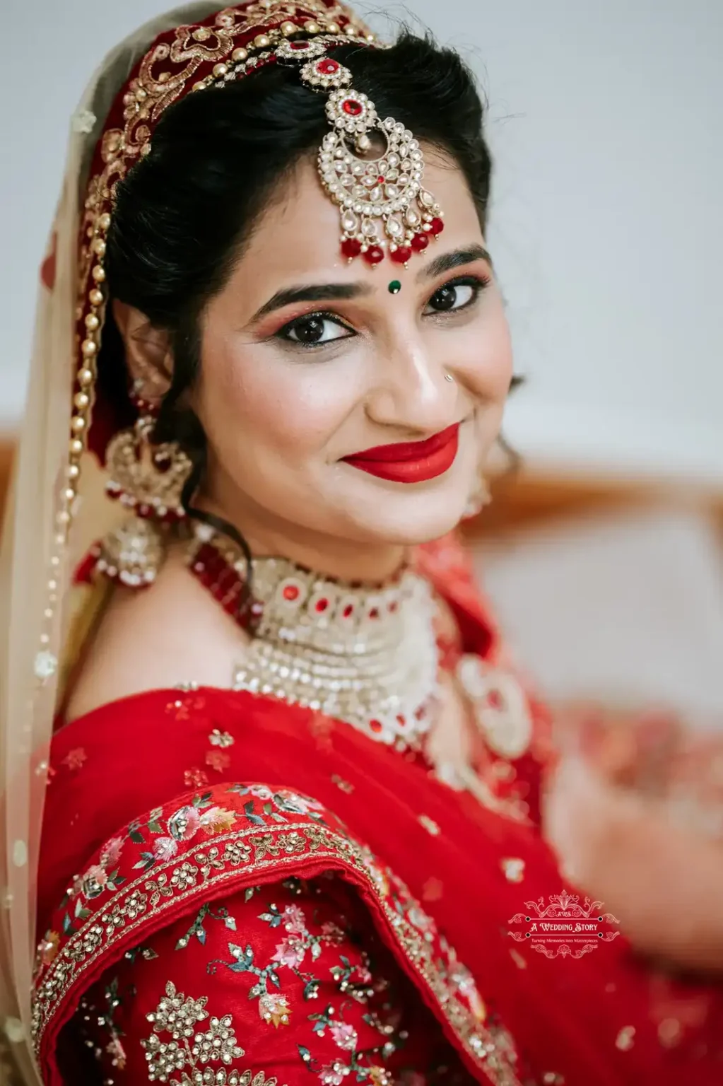 Smiling bride in traditional red and gold attire with intricate jewelry, captured by Wedding Photography in Wellington