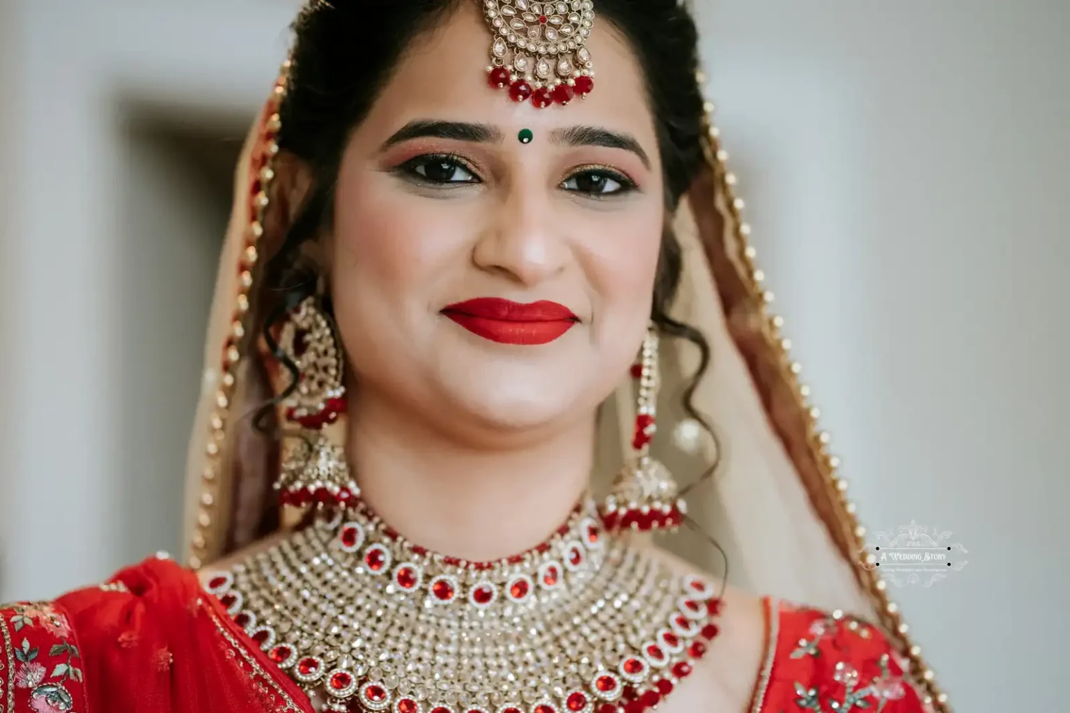 Close-up of the bride smiling in red bridal attire and traditional jewelry, captured by Wedding Photography in Wellington