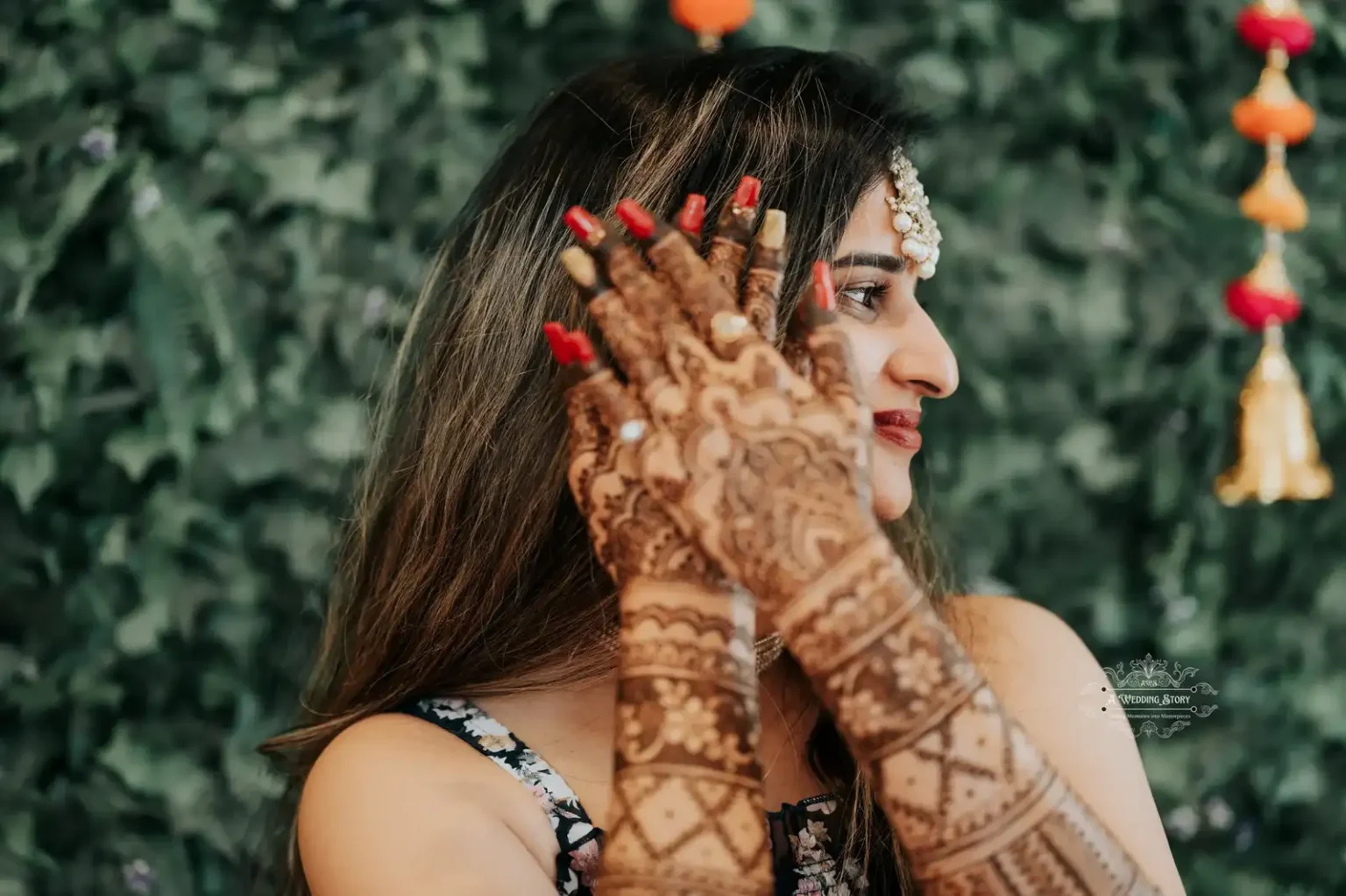 Side profile of a bride showcasing her intricately designed mehndi with a serene expression, captured against a lush green backdrop during a pre-wedding celebration in Wellington