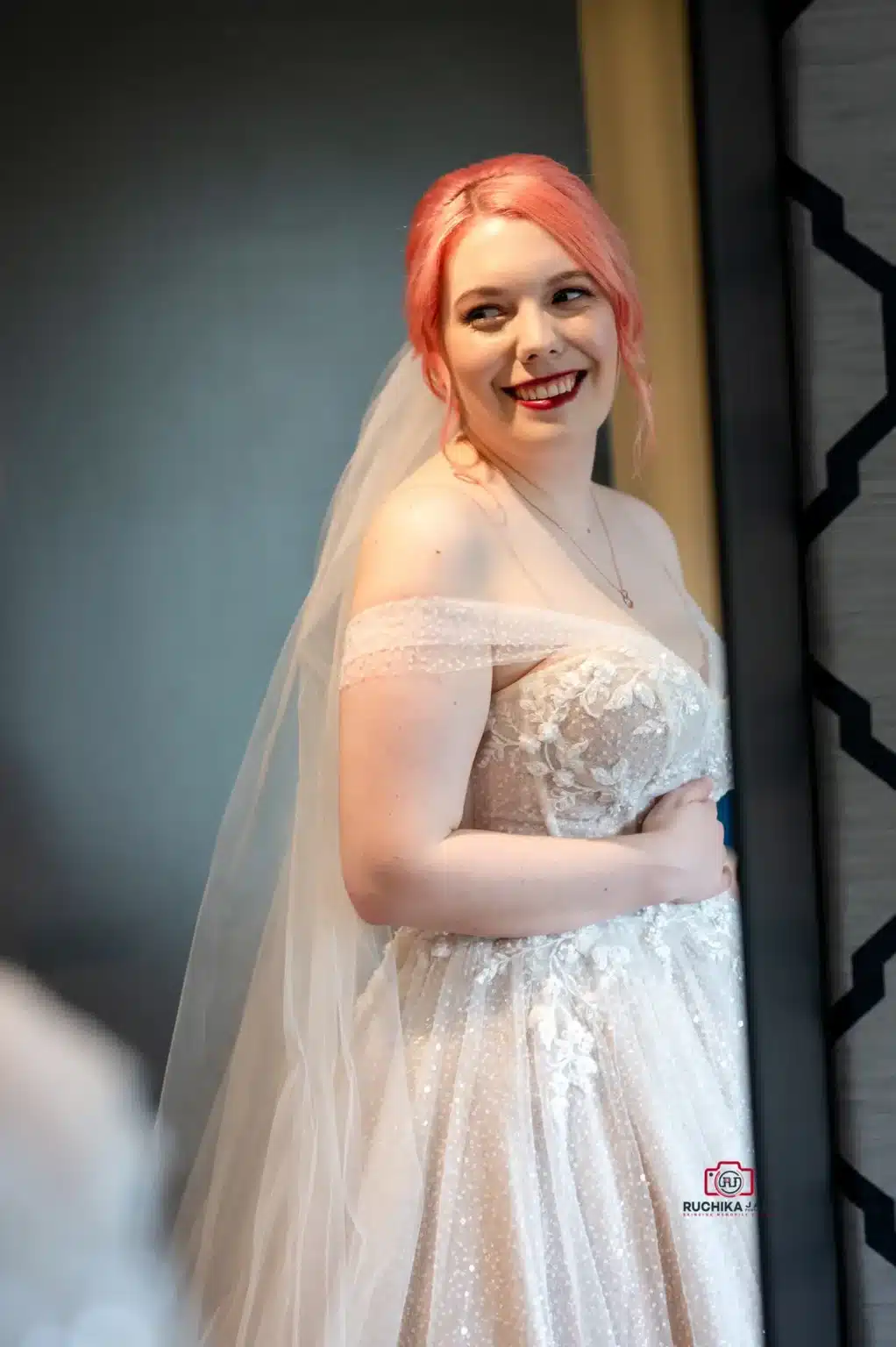 Smiling bride with pink hair in an off-the-shoulder wedding gown