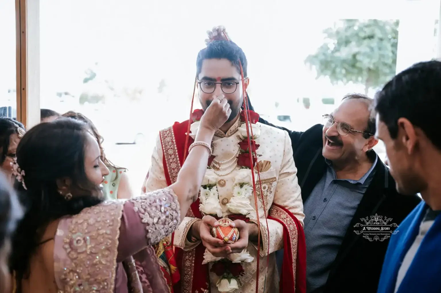 A groom in traditional attire holding an ornate ornament, as a woman performs a ceremonial ritual at a wedding in Wellington