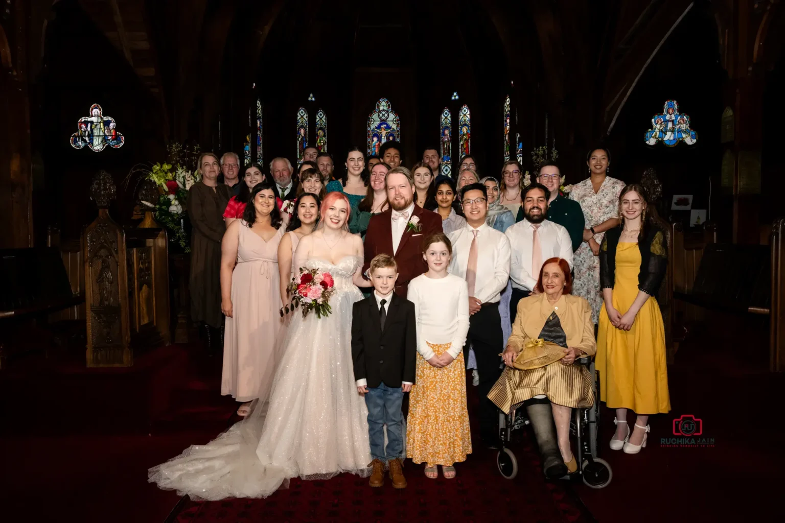 Bride and groom posing with family and friends in a church group portrait.