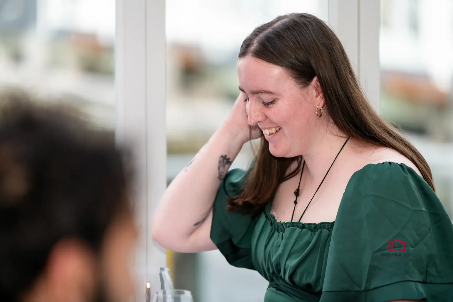 Wedding guest in green dress smiling and looking down in a candid moment