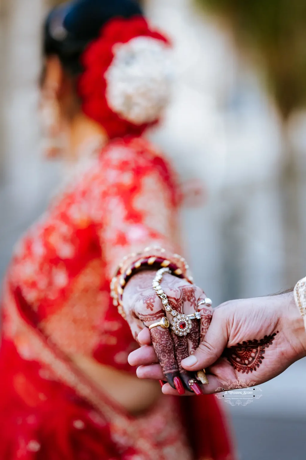 Close-up of bride and groom holding hands, showcasing intricate henna and jewelry details during their wedding in Wellington, New Zealand.