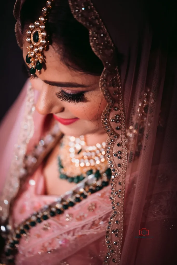 Close-up portrait of a bride in a pink lehenga with intricate embroidery, adorned with traditional jewelry and a graceful smile, captured in New Zealand