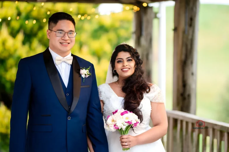 Zara and Andrew posing at their Wellington wedding under a wooden gazebo surrounded by lush greenery