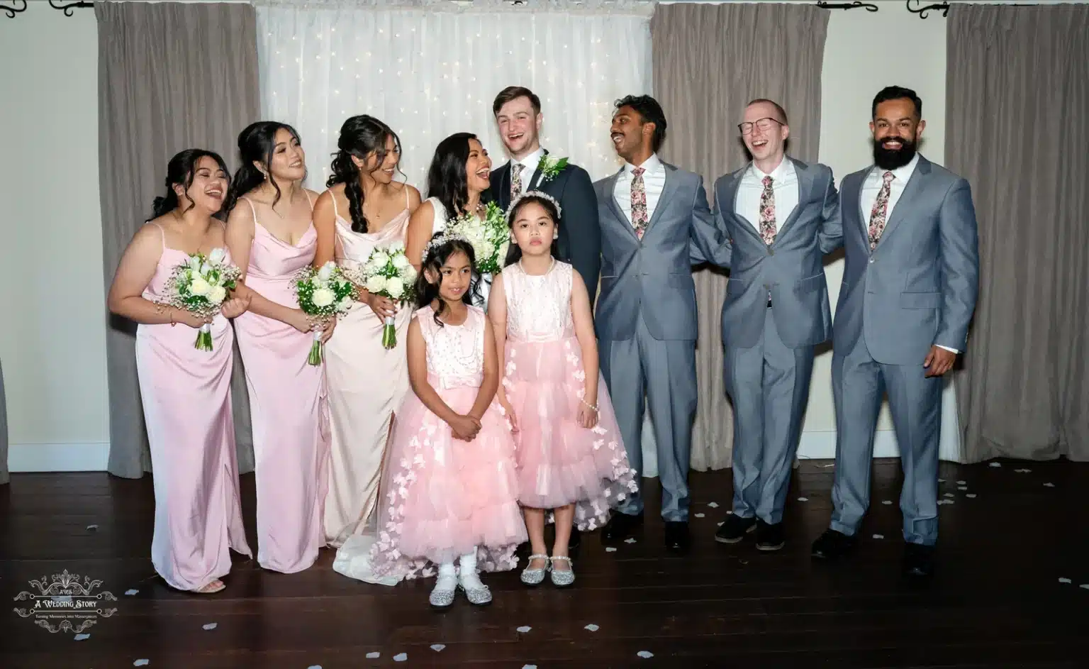 Bride, groom, bridesmaids, groomsmen, and flower girls sharing a joyful moment during the wedding celebration.