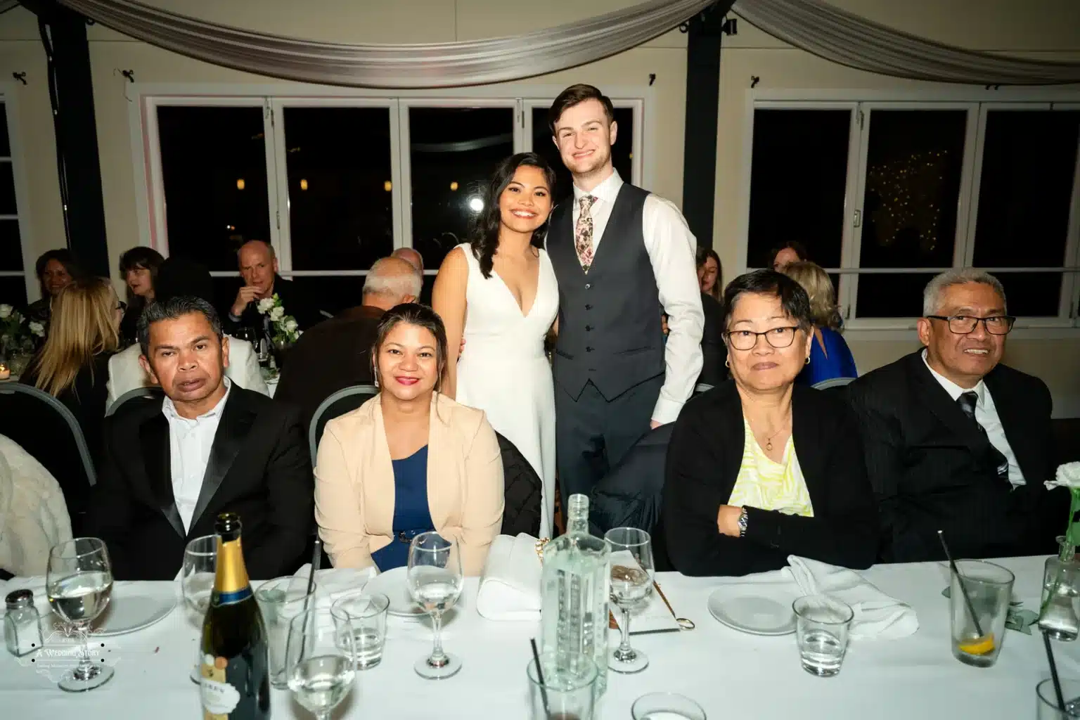 Bride and groom posing for a photo with family at their wedding reception in Wellington.