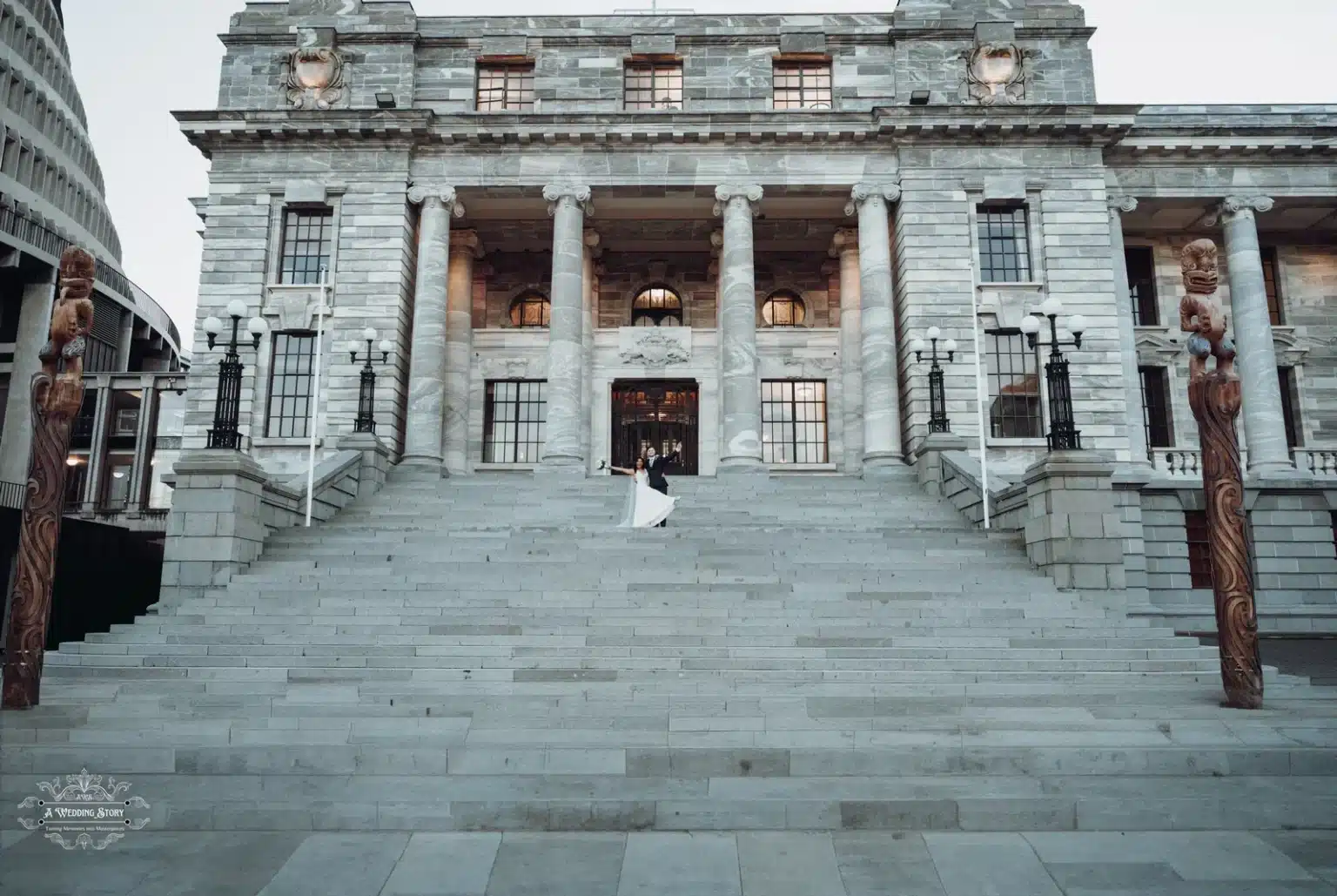 Bride and groom pose playfully on the iconic steps of Wellington’s Parliament building.