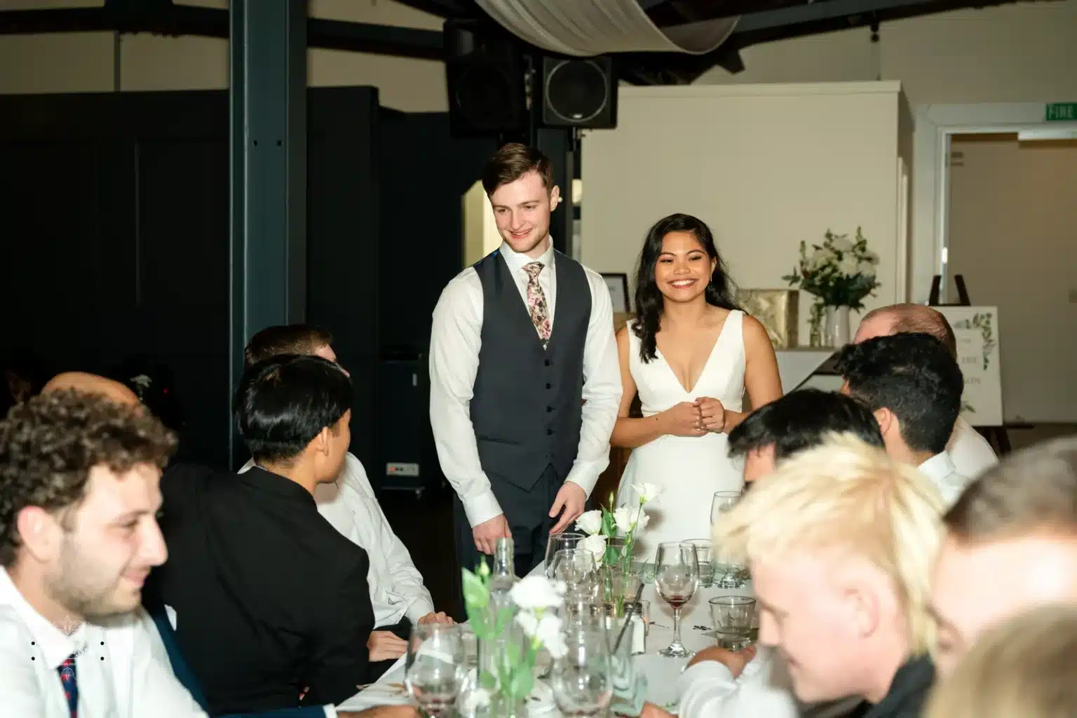 Bride and groom greeting guests during the wedding reception, standing at the head of the table.