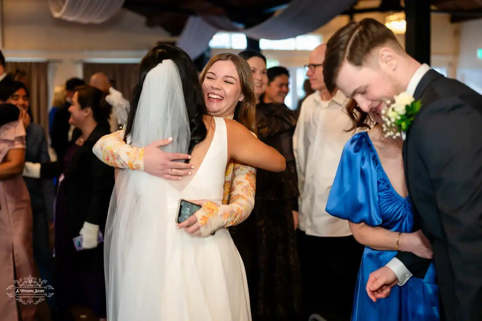 Bride in a white gown sharing a heartfelt embrace with a guest during a joyful wedding celebration in Wellington, New Zealand.