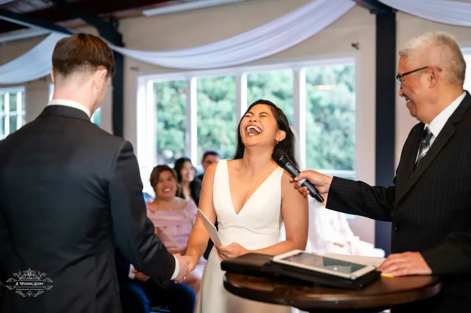 A bride laughing joyfully during her wedding ceremony while exchanging vows, captured alongside the groom and celebrant in Wellington.