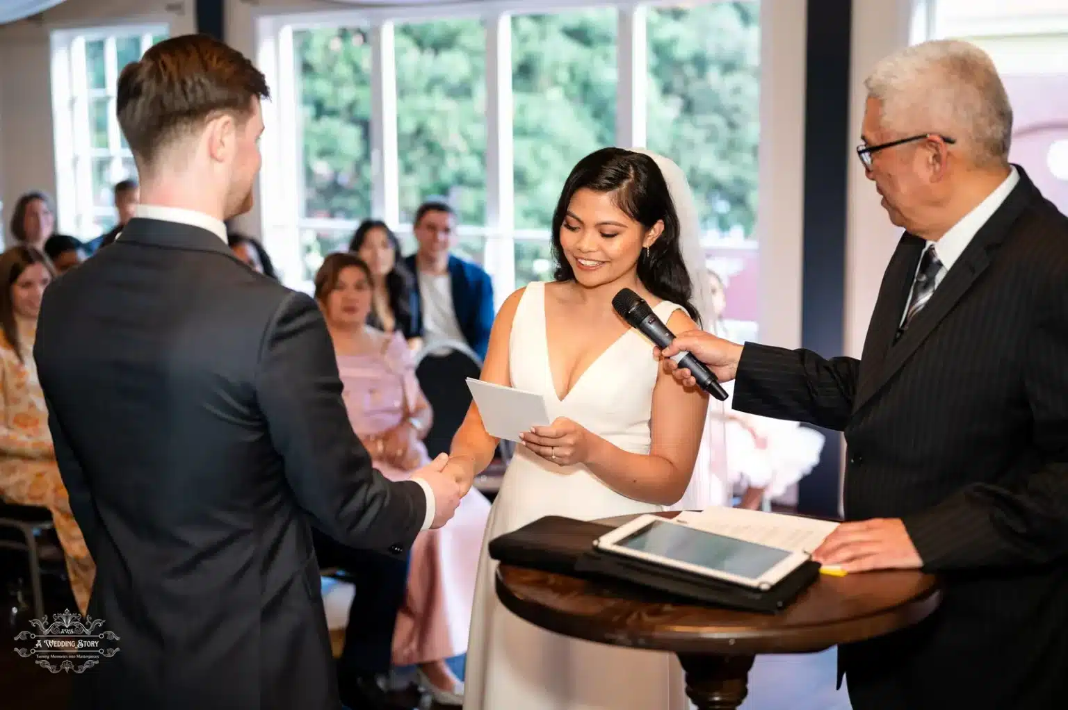 Bride holding a vow card while exchanging heartfelt promises with the groom, accompanied by the celebrant in a Wellington wedding ceremony.