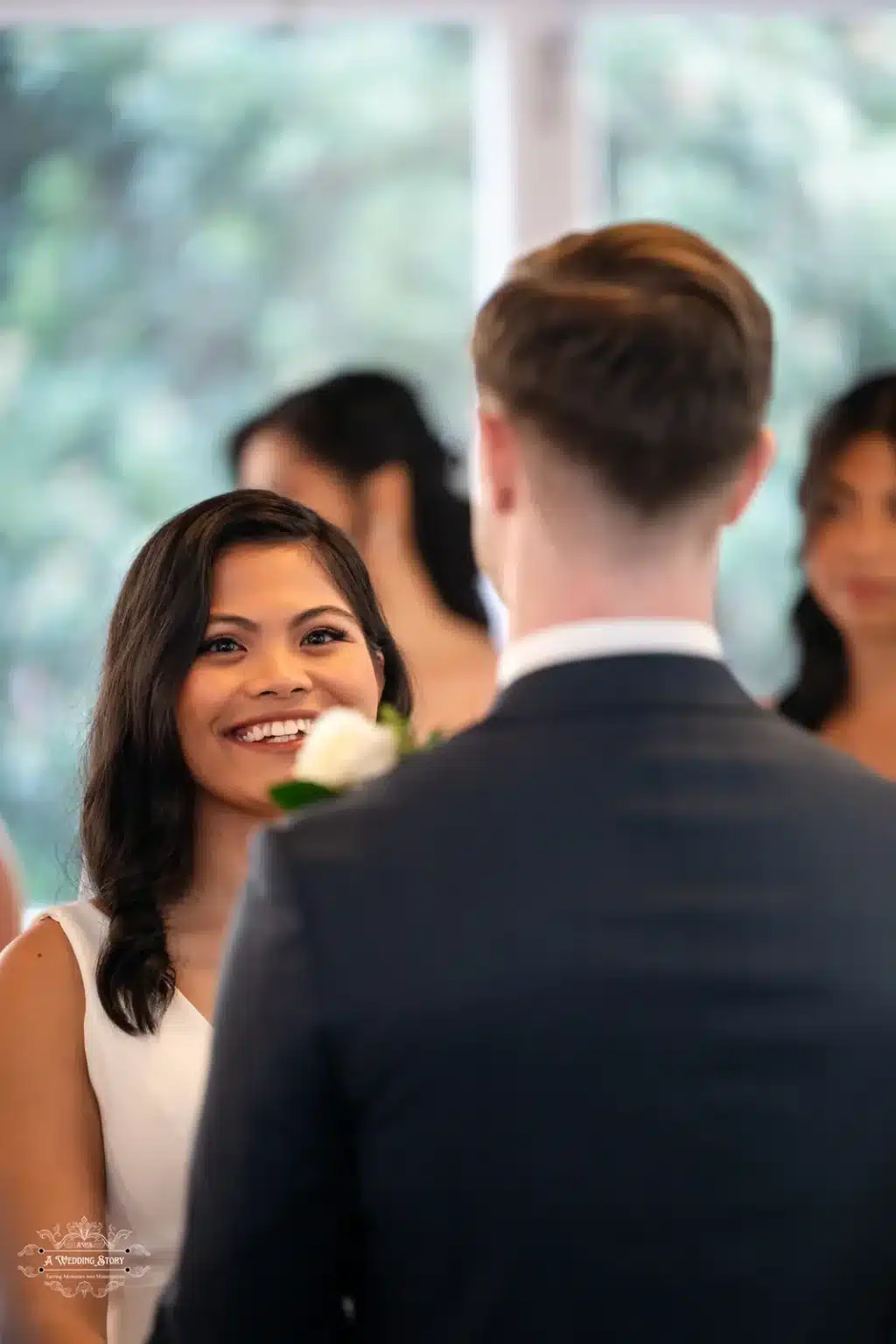 A close-up of the bride's radiant smile as she looks lovingly at her groom while exchanging vows during their wedding ceremony.