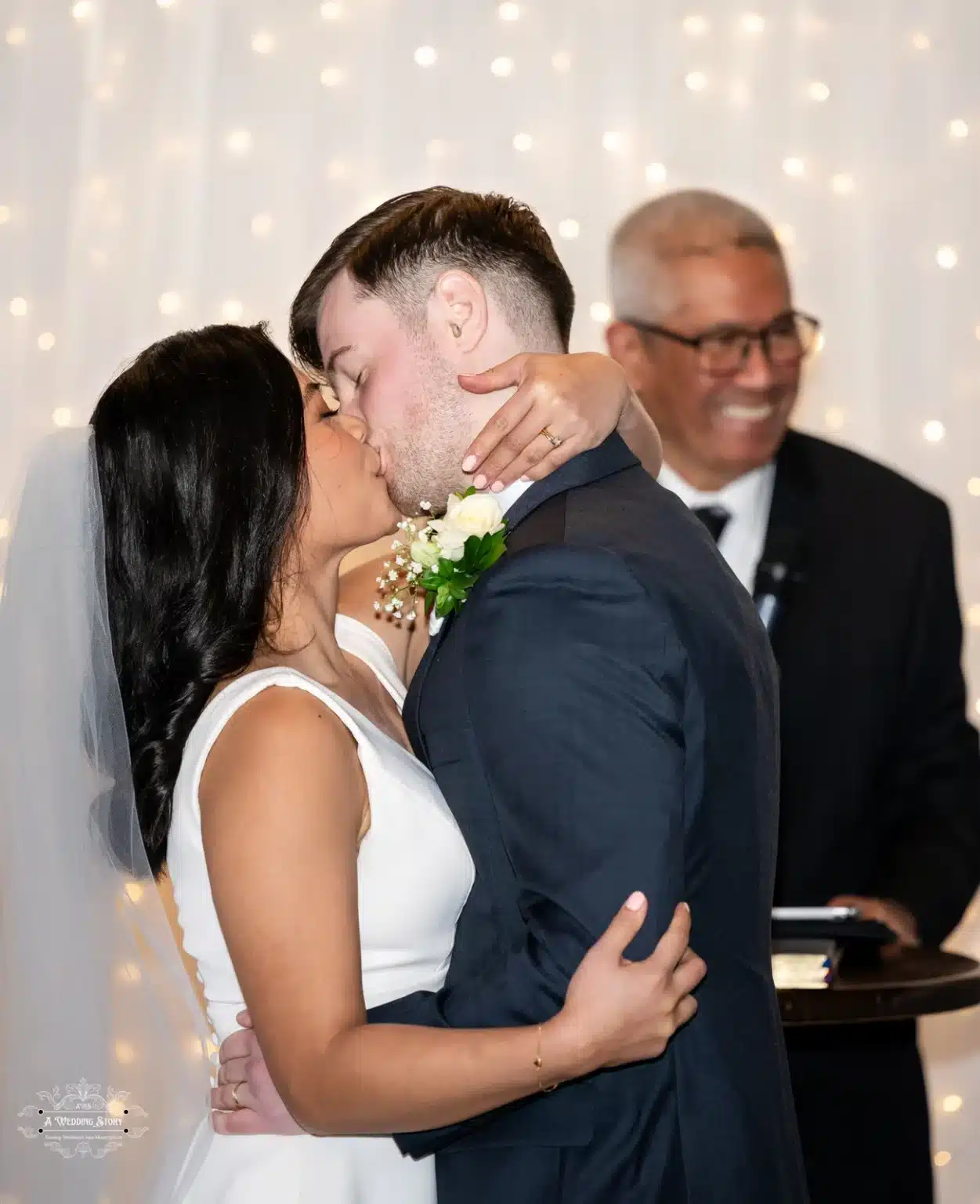 Bride and groom share their first kiss as husband and wife during their wedding ceremony in Wellington, New Zealand, under glowing lights.