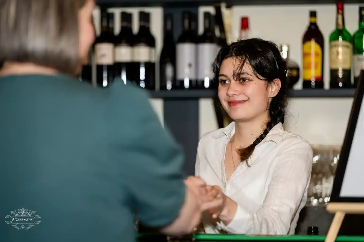 Barmaid serving drinks to a guest at a wedding reception, offering a friendly smile.