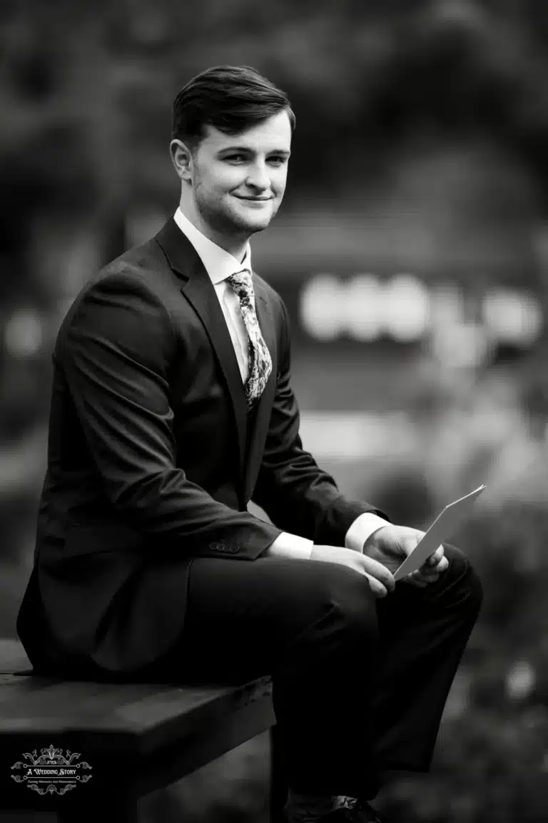 Groom holding wedding vows, seated on a bench, captured during a Wellington wedding.