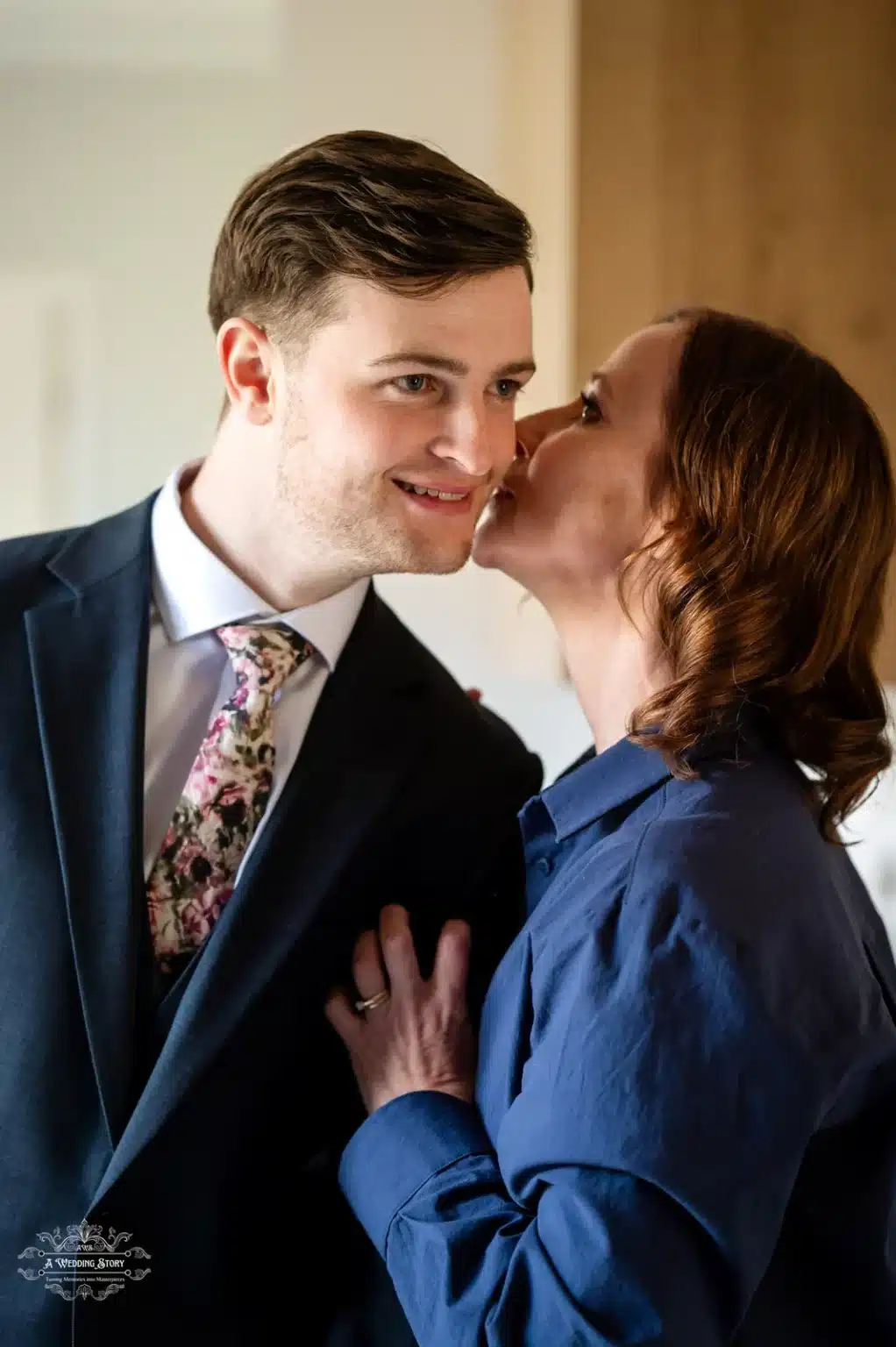 Groom smiling as his mother gives him a loving kiss on the cheek before the wedding ceremony in Wellington, New Zealand.