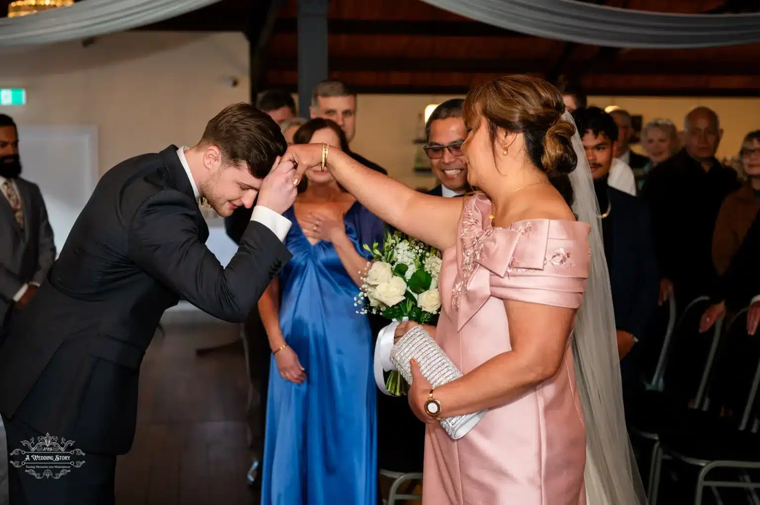 The groom respectfully bows his head as the bride’s mother gives her blessings during an emotional moment at a Wellington wedding ceremony.