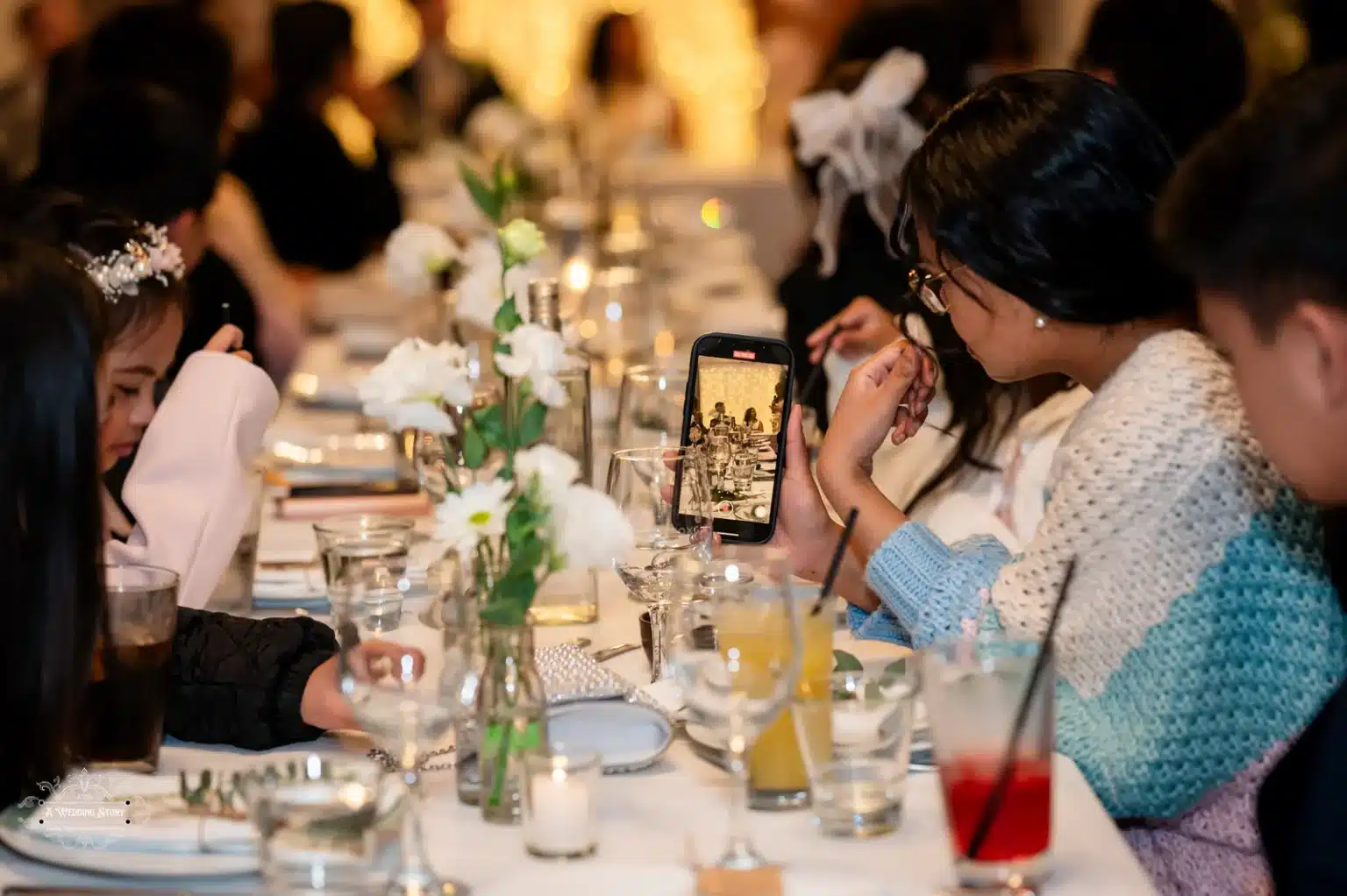 Wedding guests viewing photos on their phones at the reception table in Wellington.