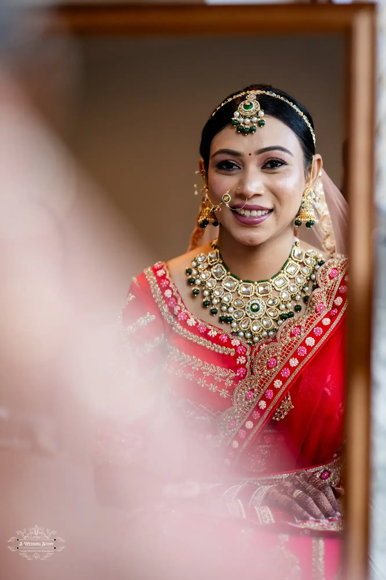 A stunning close-up of a Gujarati bride in Wellington, showcasing her elegant red lehenga, intricate gold jewelry, and traditional makeup.