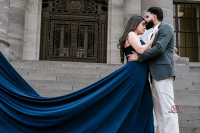 Groom giving bride a gentle forehead kiss on the steps of Wellington Parliament, with a flowing blue dress