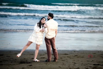 Bride playfully leaning on groom with one leg in the air during their beach elopement in Wellington