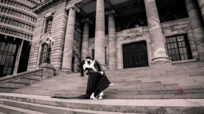 Bride and groom sharing a romantic dip on the steps of Wellington Parliament in a black-and-white photo