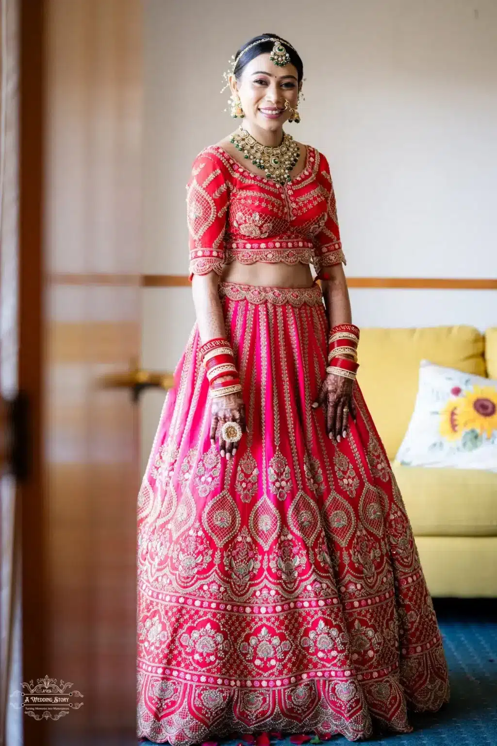 A radiant Gujarati bride in a vibrant red lehenga adorned with intricate golden embroidery and traditional bridal jewelry, captured in a softly lit room.