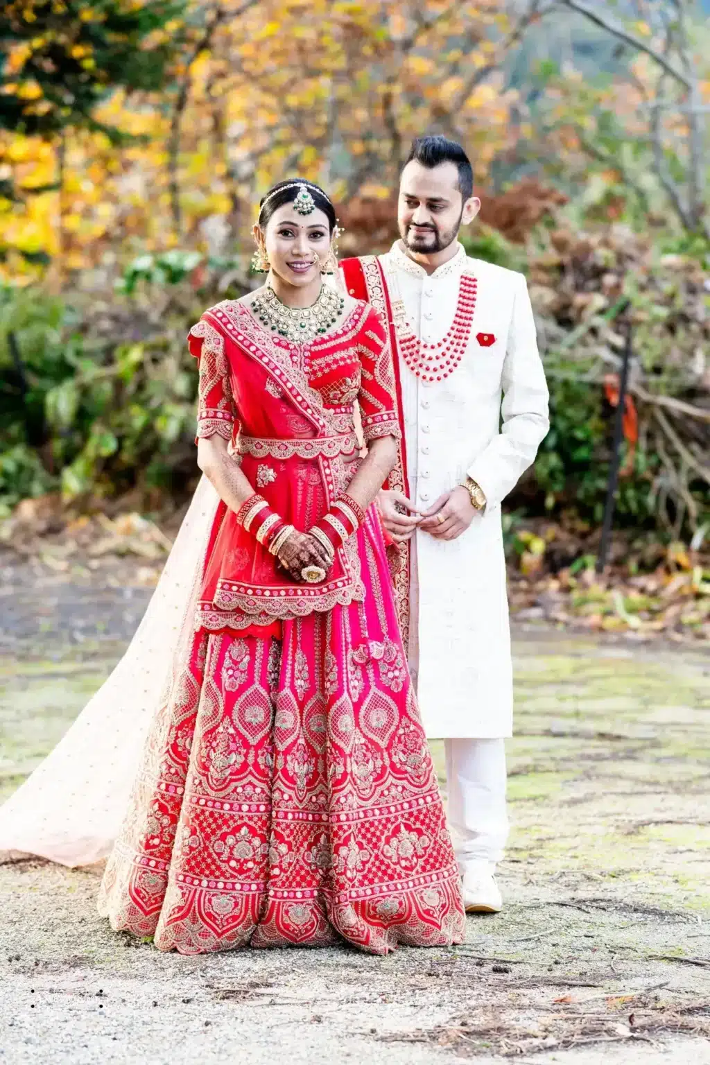 Gujarati bride in a traditional red lehenga and groom in a white sherwani posing during their wedding photoshoot in Wellington, New Zealand