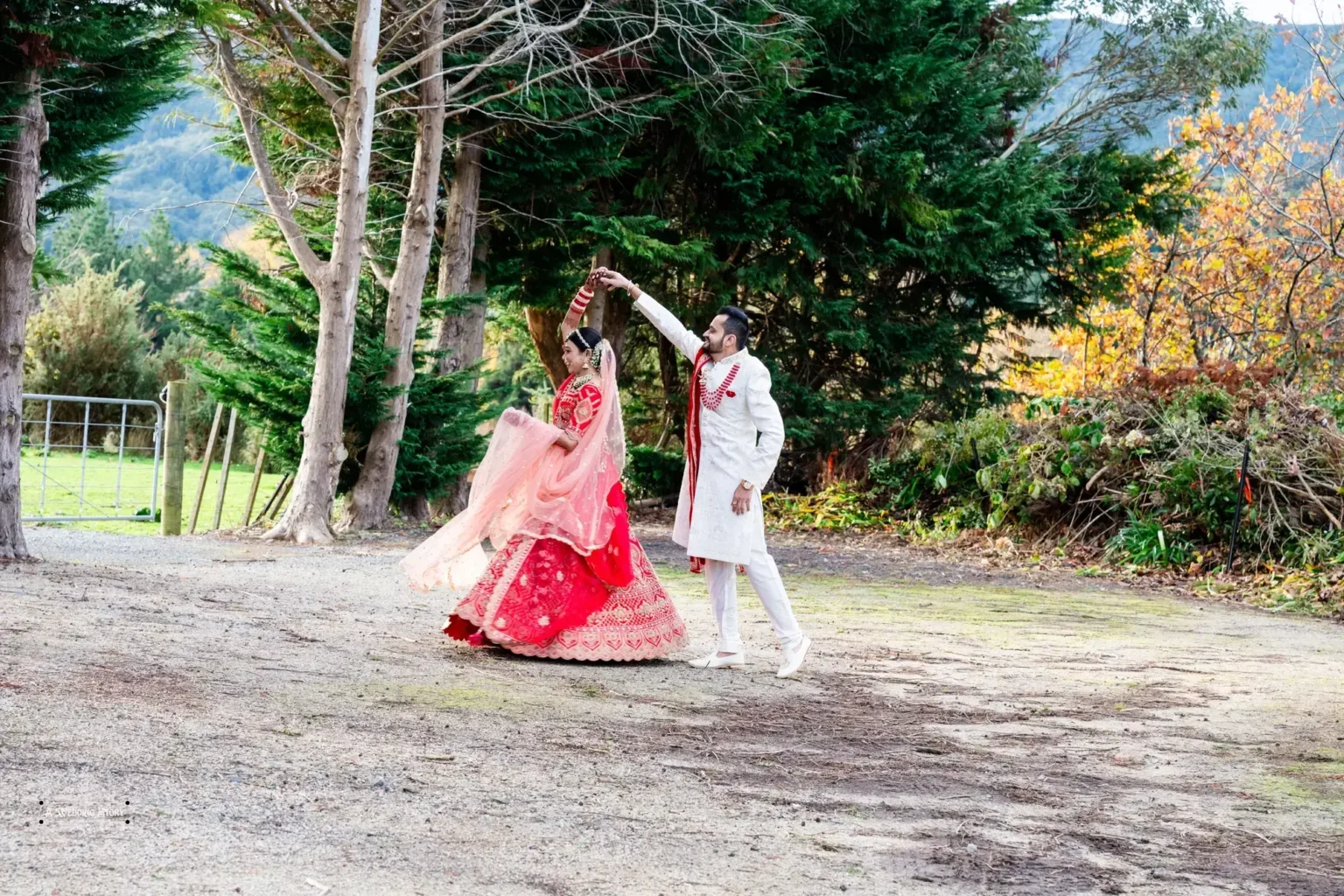 Bride and groom sharing a romantic twirl during their Gujarati wedding photoshoot in Wellington, surrounded by scenic greenery and autumn hues.