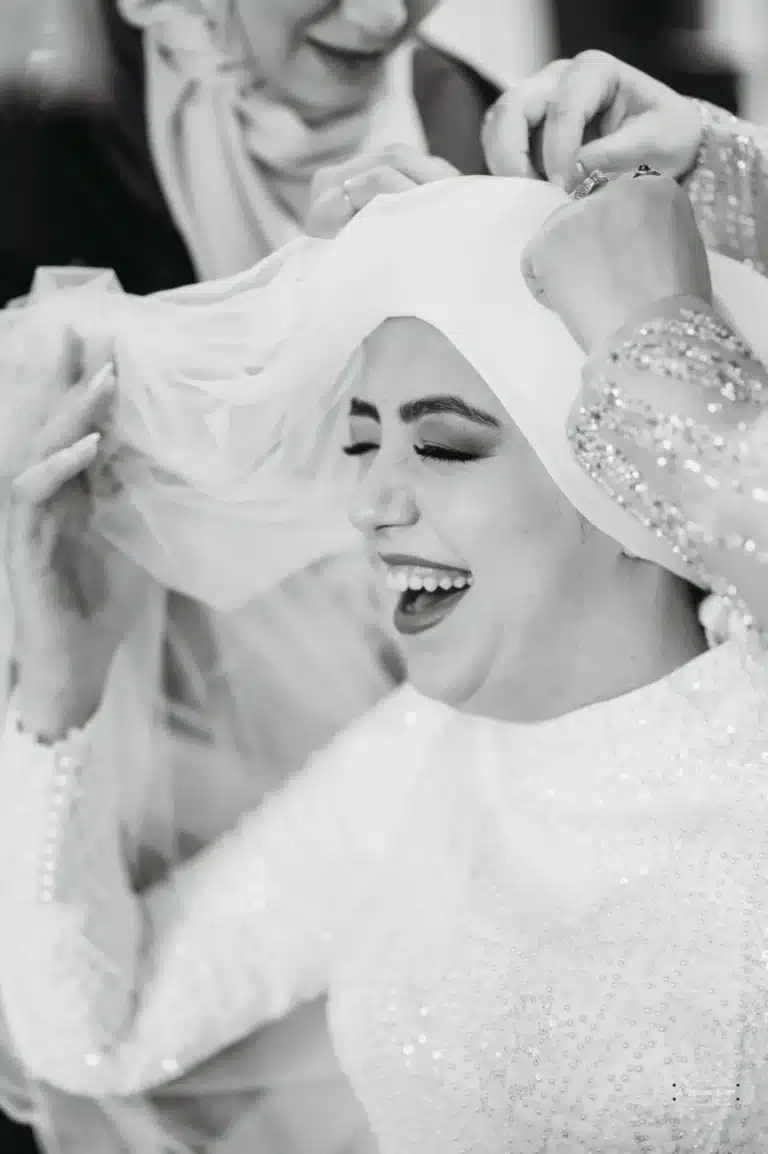 Afghan bride laughing as family members adjust her veil during her wedding preparations in Wellington.