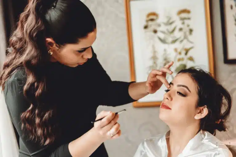 Afghan bride receiving makeup touches from an artist, preparing for her wedding day in Wellington.