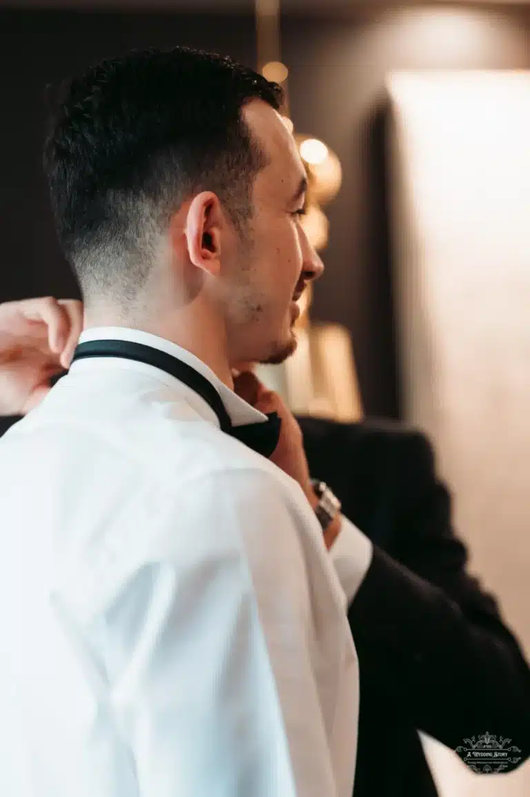 Side view of Afghan groom being assisted with his bow tie before his wedding in Wellington.