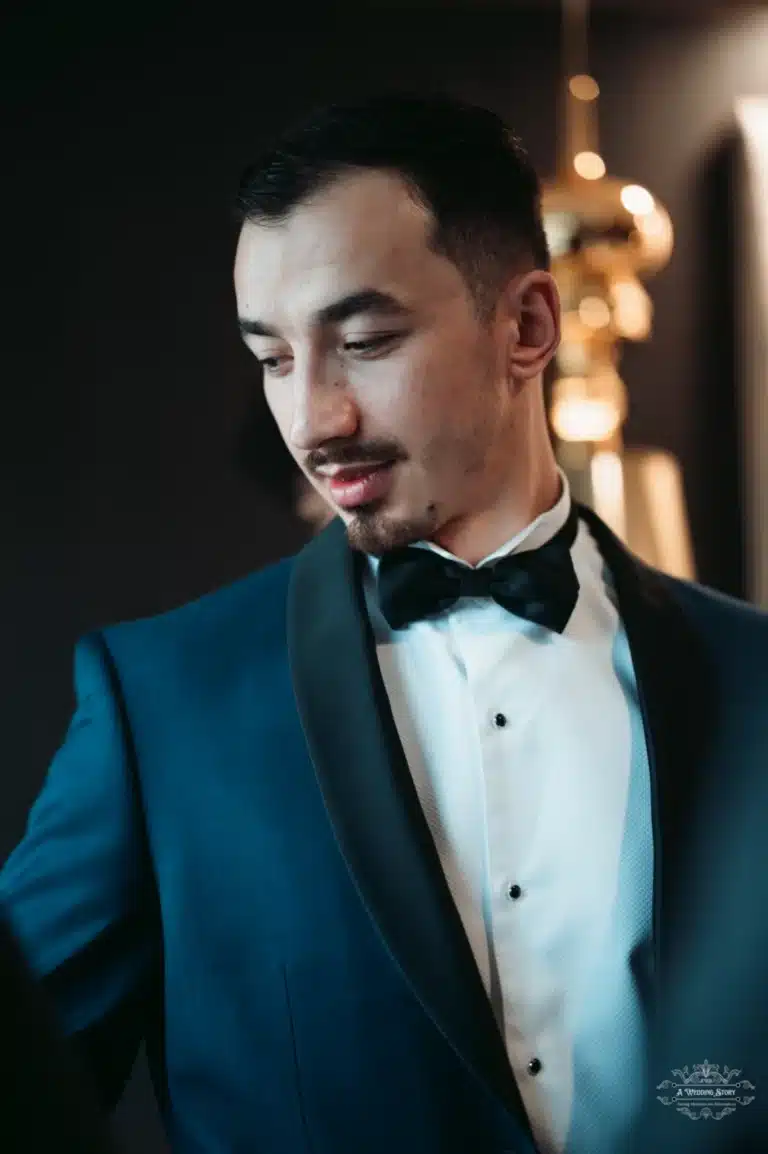 Afghan groom wearing a tuxedo and bow tie, looking down thoughtfully on his wedding day in Wellington.